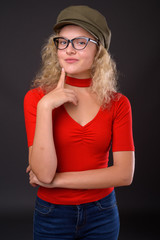 Young beautiful woman with blond curly hair against gray backgro