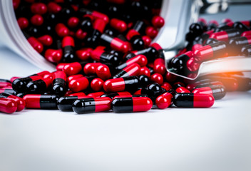 Wall Mural - Red-black antibiotic capsule pills spill out of white plastic bottle container and drug tray. Pharmaceutical industry. Prescription drug. Global healthcare. Antimicrobial drug resistance. Pharmacy.