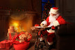 © ty - Portrait of happy Santa Claus sitting at his room at home near Christmas tree and answering Christmas letters.