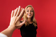 Excited woman looking camera give a high five to someone's hand isolated over red background.