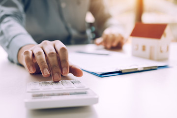 Close up of finger businessman using calculator calculate budget about house contract mortgage in the office room.