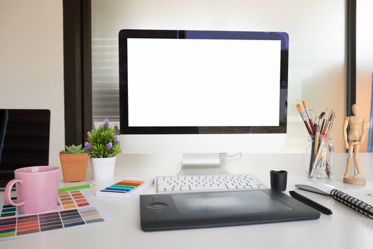 Mockup artist workplace with computer pc and cup of coffee on desk with empty screen computer display.