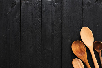 Wall Mural - wooden spoons on black wooden background with copy space. top view of various types of wooden spoons