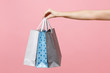 © ViDi Studio - Close up female holds three colored clear empty blank craft paper gift bag for purchases after shopping isolated on pastel pink background. Packaging template mockup. Delivery concept advertising area