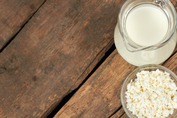 Wall Mural - Dairy products on vintage wooden boards. Milk in glass pitcher and cottage cheese in bowl on wooden background with copy space.