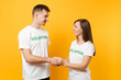 © ViDi Studio - Portrait of young colleagues couple in white t-shirt with written inscription green title volunteer isolated on yellow background. Voluntary free work, assistance help, charity grace teamwork concept.