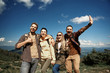 © Yakobchuk Olena - Low angle waist up portrait of jolly two men and two women standing and embracing. Tourists are laughing and raising arms for showing funny gestures