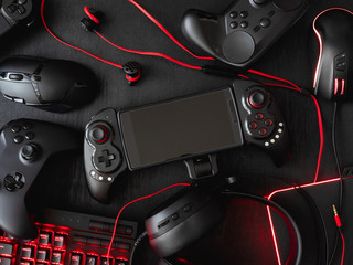 Poster - gamer workspace concept, top view a gaming gear, mouse, keyboard, joystick, headset, mobile joystick, in ear headphone and mouse pad on black table background.