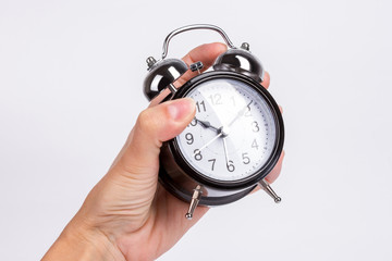 female hands squeezes black alarm clock isolated