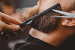 Close-up of barber shearing beard to man in barbershop
