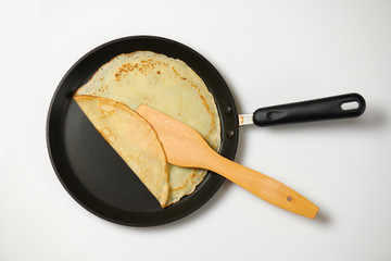 Crepe closeup, thin pancake on a frying pan, white background