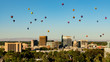 Many hot air balloons of different shapes and colors over the Boise Skyline