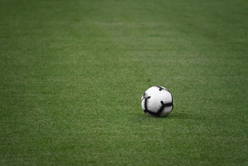 single white football ball on the green lawn of a sports stadium. football match. sports competition. ball on the field