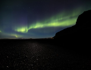 Wall Mural - aurora borealis over reynisfjara black sand beach in iceland as the moon lights up the glaciers in t