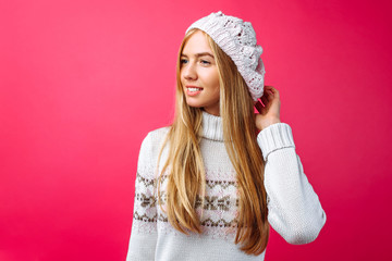 Beautiful girl standing isolated on red background, in warm pink hat .