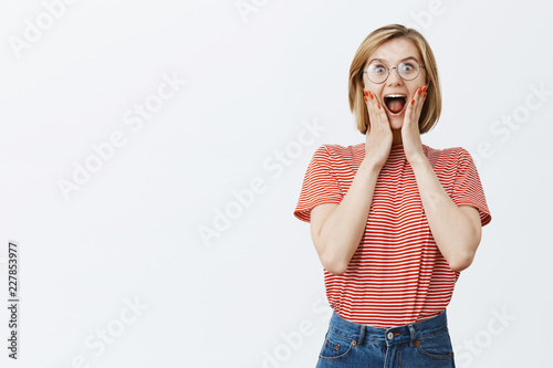 Happy Thrilled And Joyful Female Fan With Blond Hair In Glasses Screaming From Joy And Excitement Holding Hands On Cheeks Being Impressed And Overwhelmed With Emotions Seeing Famous Rockstar Buy This