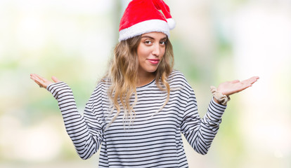 Poster - Beautiful young blonde woman wearing christmas hat over isolated background clueless and confused expression with arms and hands raised. Doubt concept.