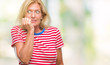 © Krakenimages.com - Middle age blonde woman over isolated background looking stressed and nervous with hands on mouth biting nails. Anxiety problem.