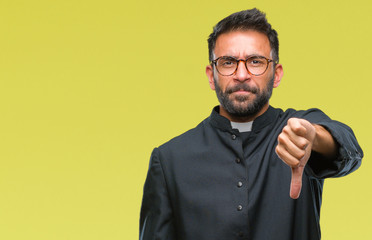 Adult hispanic catholic priest man over isolated background looking unhappy and angry showing rejection and negative with thumbs down gesture. Bad expression.