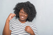 © Krakenimages.com - Young african american plus size woman over grey grunge wall very happy and excited doing winner gesture with arms raised, smiling and screaming for success. Celebration concept.
