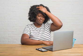 Sticker - Young african american woman sitting on the table using computer laptop stressed with hand on head, shocked with shame and surprise face, angry and frustrated. Fear and upset for mistake.