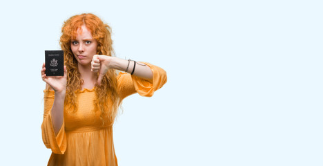 Sticker - Young redhead woman holding passport of United States of America with angry face, negative sign showing dislike with thumbs down, rejection concept