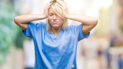 Wall Mural - Young beautiful blonde nurse doctor woman over isolated background suffering from headache desperate and stressed because pain and migraine. Hands on head.