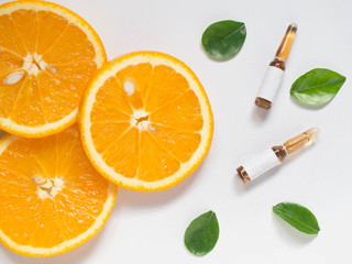 Wall Mural - Vitamin C brown ampule for injection with fresh juicy orange fruit slices on white table. High dose vitamin c synthetic for white skin. Beauty product branding mock-up. Healthy lifestyle. Top view.