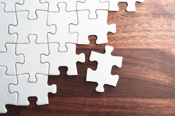 Aufkleber - Unfinished white jigsaw puzzle pieces on wood table.Assembling jigsaw puzzle pieces. Abstract background.