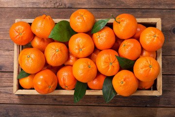 Poster - Fresh mandarin oranges fruit or tangerines with leaves in wooden box