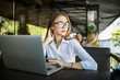 © F8  \ Suport Ukraine - Concentrated at work. Confident young woman in smart casual wear and glasses working on laptop while sitting in creative office or cafe