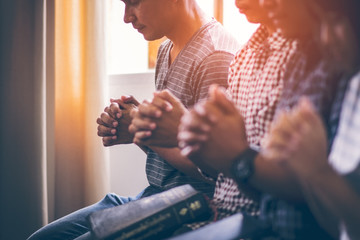 Wall Mural - Asian Christian groups sitting within the Church Catholic. They clasped hands and closed his eyes and prayed for blessings from God. A pale sun shone in a place of worship. Everyone smiled happily.