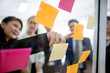 © saksit - Business people meeting at office and explaining to colleagues over sticky notes in office brainstorm strategy workshop