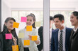 © saksit - Business people meeting at office and explaining to colleagues over sticky notes in office brainstorm strategy workshop
