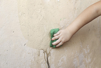 children's hand washes a wet sponge wall..the child makes a wet cleaning, clean the rough surface from the dirt.