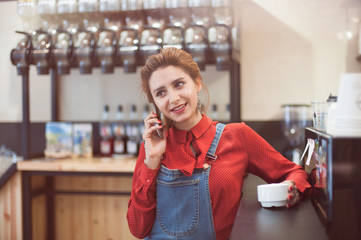 happy smiling young caucasian girl calling cell phone sitting in coffee bar