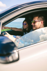 Happy young man driving a car accompanied by his girlfriend