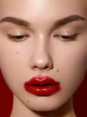 Wall Mural - Cosmetics, makeup and trends. Bright lip gloss and lipstick on lips. Closeup of beautiful female mouth with red lip makeup. Beautiful part of female face. Perfect clean skin in red light