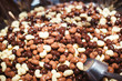 Chocolate candies background closeup. Chocolates candy made with black, white and milk chocolate. Chocolate covered nuts and raisins background. Natural candies in big basket to your choice.