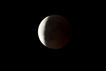 Wall Mural - super bloody moon, full eclipse end phase against black sky background, three-quarters of the moon s