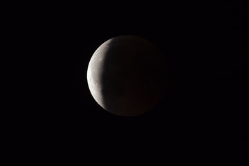 Wall Mural - super bloody moon, full eclipse end phase against black sky background, three-quarters of the moon s
