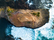 Overhead birds eye view of rock island surrounded by crashing waves