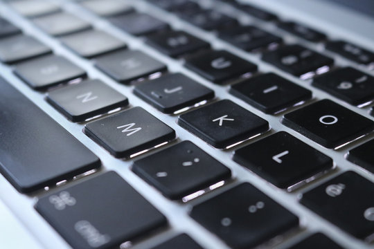 Primo piano di una tastiera di computer, messa a fuoco su lettere M,K,O, vista dall’alto