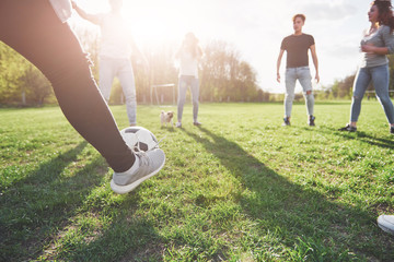 A group of friends in casual outfit play soccer in the open air. People have fun and have fun. Active rest and scenic sunset