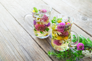 Wall Mural - Two glass mugs of healthy herbal tea with medicinal herbs with copy space.