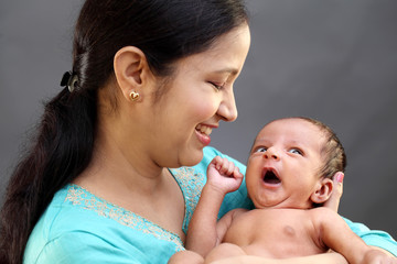 cheerful mother playing with newborn baby