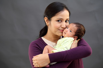 cheerful mother playing with newborn baby