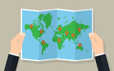 Fototapeta Mapy - Hands hold folded paper map of world with markers