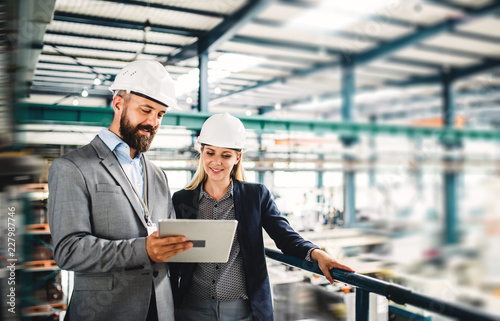 A portrait of an industrial man and woman engineer with tablet in a factory, working Poster Mural XXL