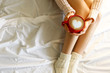 © Evrymmnt - Young woman drinking cappuccino coffee and sitting in bed with white linnen. Top view of female legs in warm wool socks & sweater. Comfort winter holidays concept. Close up, copy space, background.